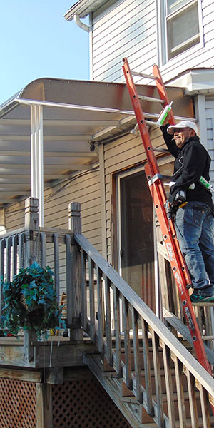 A man on a ladder in front of a house.
